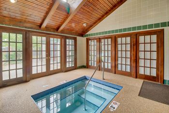 Indoor swimming pool in a room with windows and a wooden ceiling at Hunt Club Apartments, Integrity Realty, 44321
